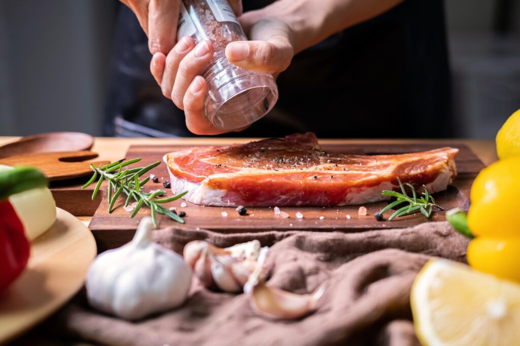 Chef prepares pork chop steak with barbecue sauce in the kitchen